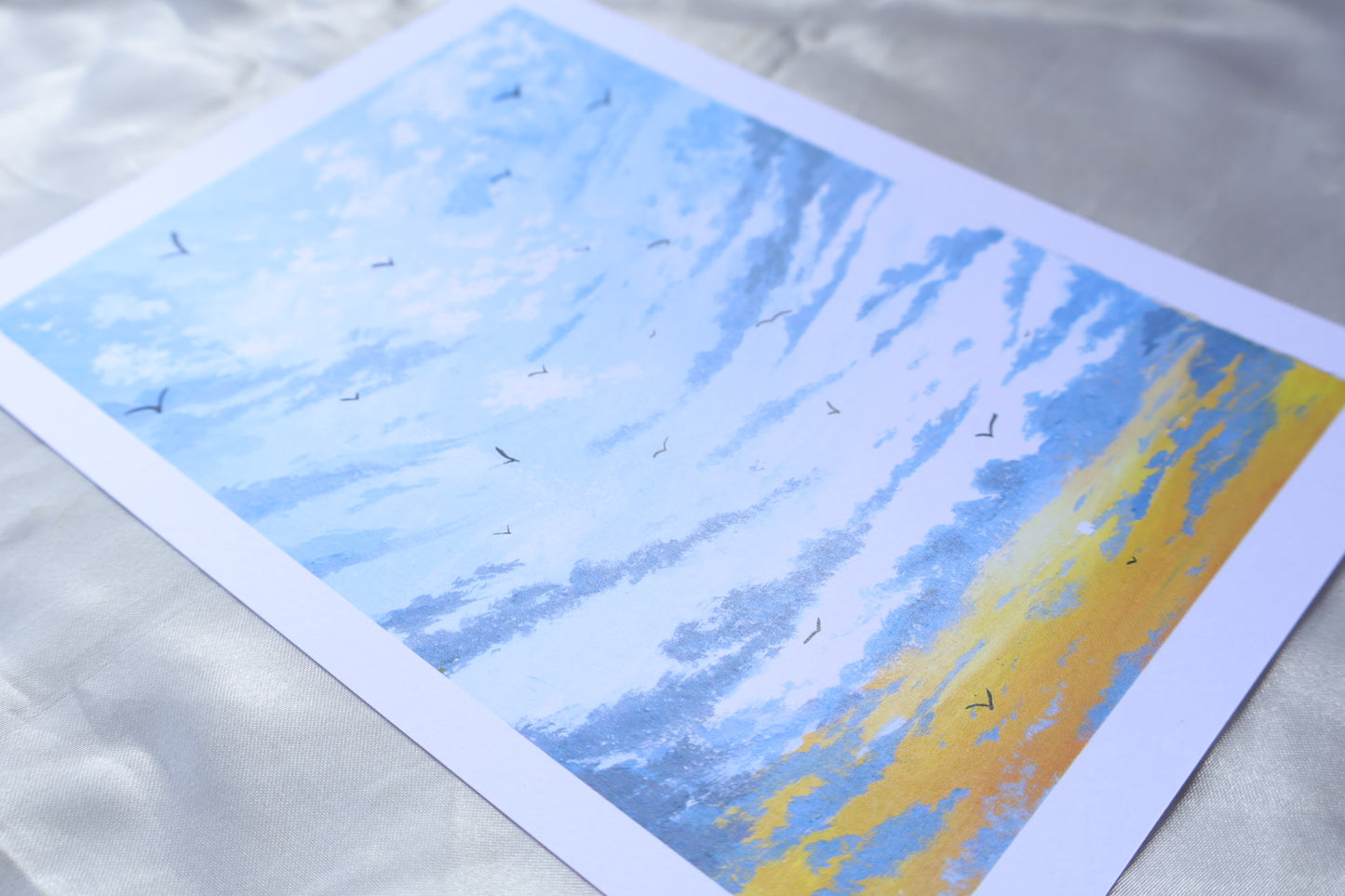 A sunrise scene portraying birds flying towards you, from white clouds at the top, and a gradient towards the bottom, blueish grey clouds, at the background of a bright yellow glow, and small sun in the bottom left.