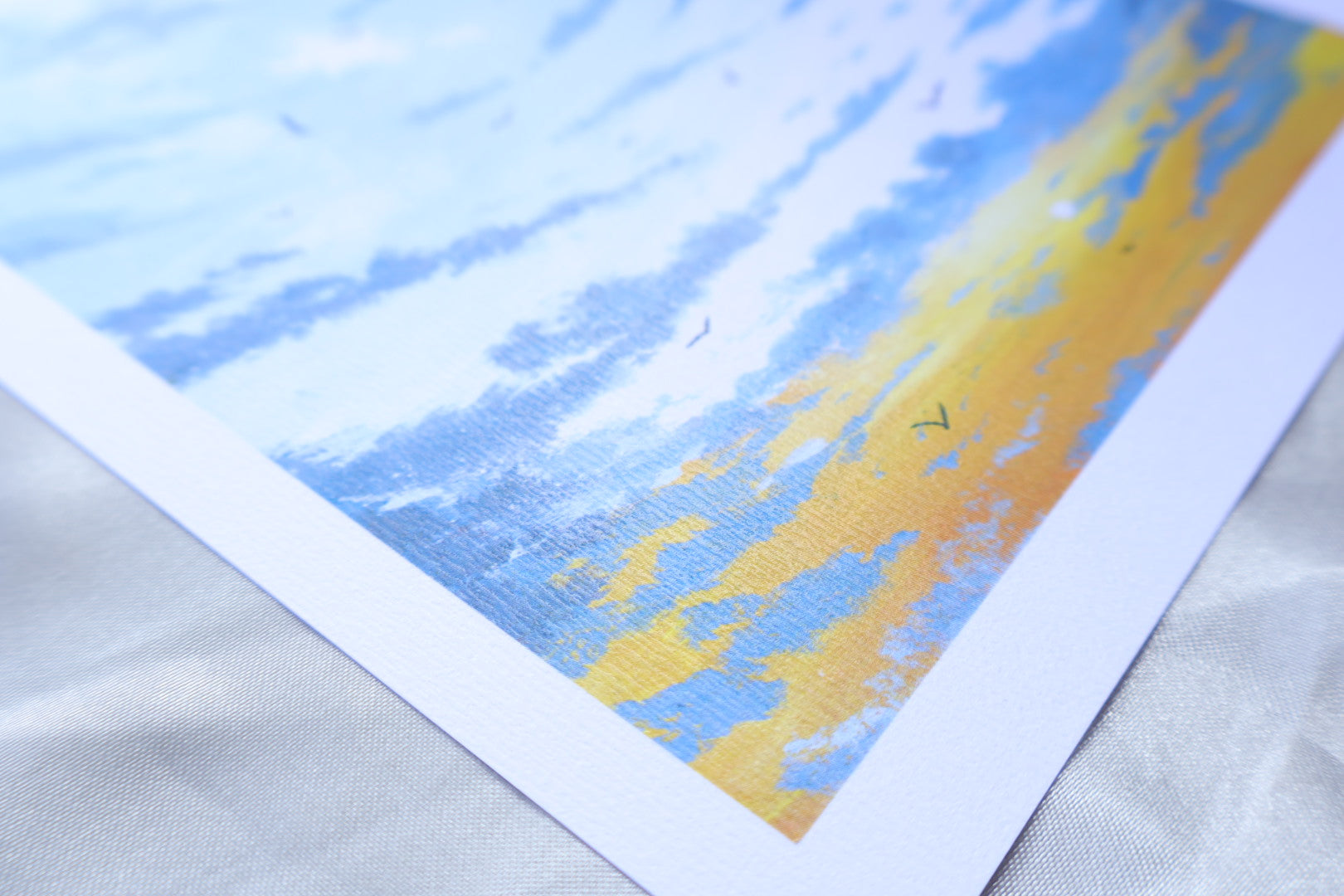A sunrise scene portraying birds flying towards you, from white clouds at the top, and a gradient towards the bottom, blueish grey clouds, at the background of a bright yellow glow, and small sun in the bottom left.