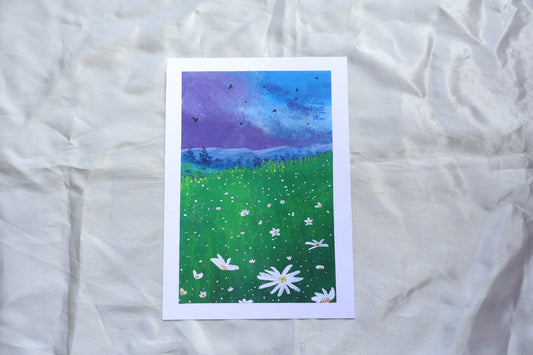 Purple bluey clouds under the dark evening blue sky, with soft mountains underneath it, covered with trees, followed by a bright foreground flowers, resembling daisies, glowing in the night sky, surrounded with yellowish and greenish tall grasses, meadow-like, and energetic birds flying in the sky.