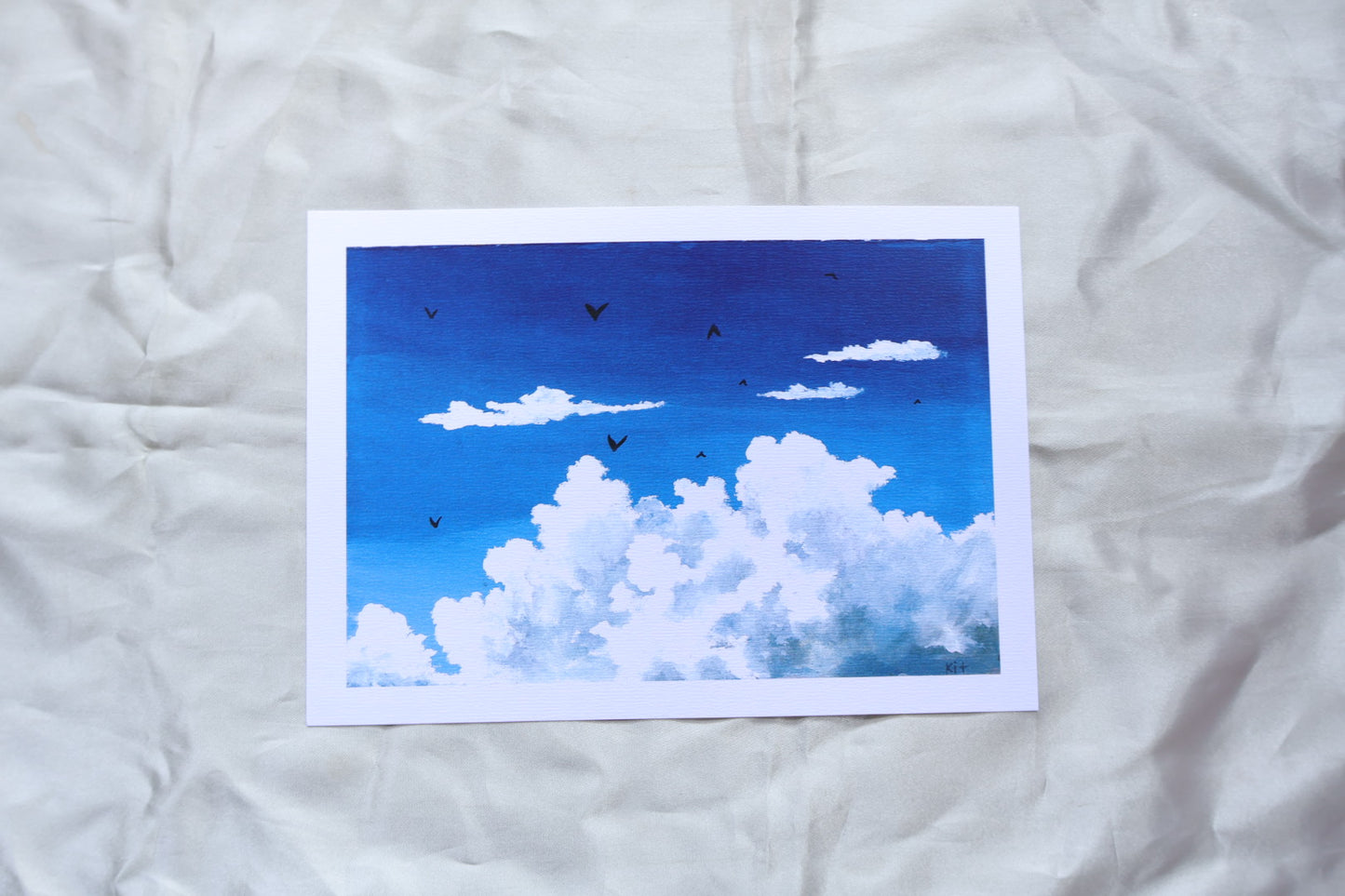 Blue sky with fluffy white clouds and birds on textured paper