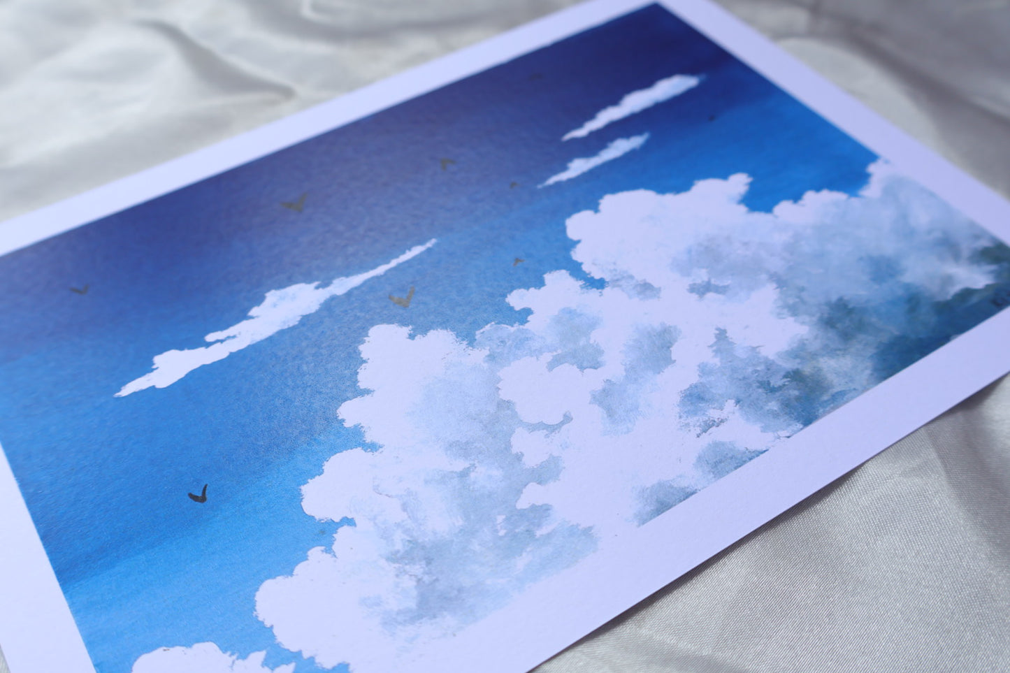 Blue sky with fluffy white clouds and birds on matte paper